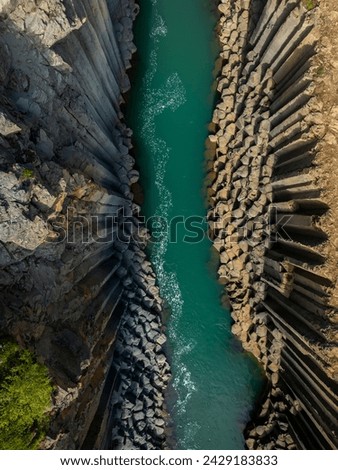 Majestic turquoise river running through unique white rock formations, directly above aerial shot. Canyon, ravine, nature, and Iceland concept.