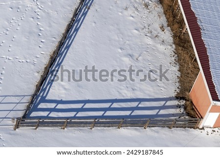 Aerial view of the acute angle of a wooden fence and the shadow it creates on the snow. Royalty-Free Stock Photo #2429187845