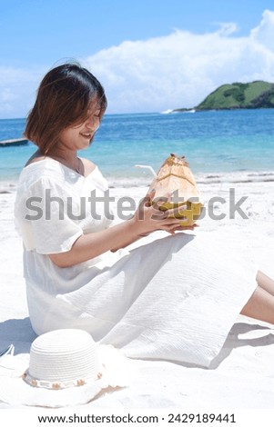 Beautiful woman enjoying young coconut on the beautiful Lombok beach