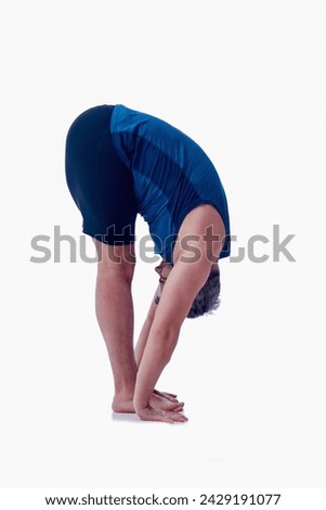Uttanasana A, Ashtanga yoga  Side view of man wearing sportswear doing Yoga exercise against white background. 