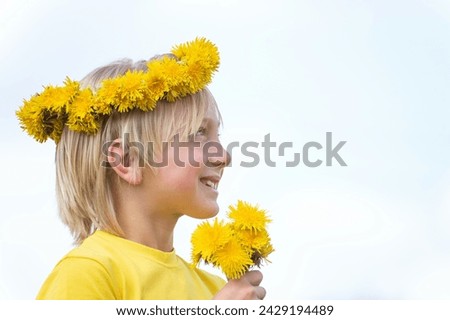 Portrait of cute smiling blond boy wearing wreath of flowers and holding bouquet of dandelions. Children naivety and spontaneity. Isolated on white background Royalty-Free Stock Photo #2429194489