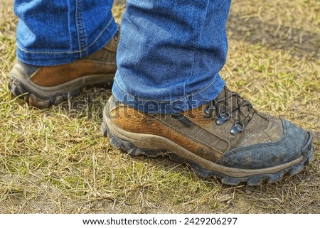a worker stands on the ground in brown leather old warm lace-up men's boots with rubber soles on his feet in blue jeans during the day on the street Royalty-Free Stock Photo #2429206297