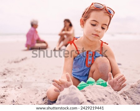 Child, beach and sandcastle building on holiday for summer travel with family for environment, playing or swimwear. Girl, seashore and outdoor in Australia with parents or recreation, fun or vacation Royalty-Free Stock Photo #2429219441