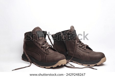 Brown leather boots with untied laces on a white background
