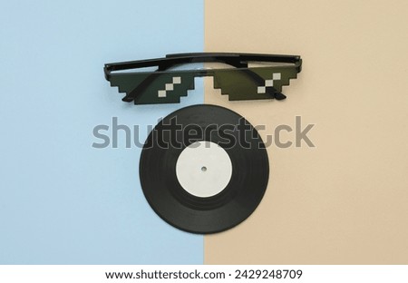 Stereo headphones with vinyl record on blue pastel background. Music concept