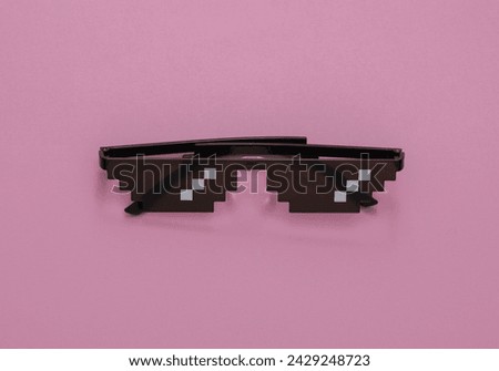Pixelated 8 bit sunglasses on pink background