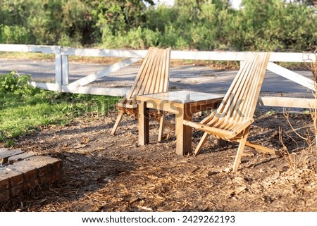 Garden furniture for leisure time in spring nature. Wooden chairs and table table in orchard. Wooden outdoor furniture set for Picnic in garden. Cozy Interior Courtyard with table and sun loungers