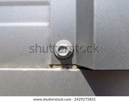 Close-up of shiny grey metal facade fastened by silver screw. Royalty-Free Stock Photo #2429275831