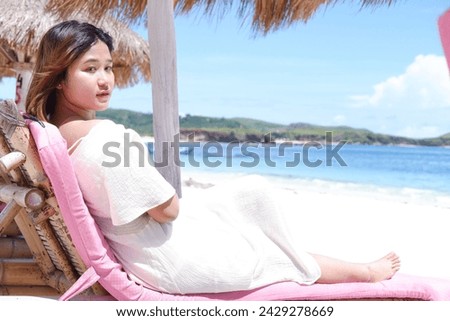 Young Asian woman in cute summer dress lying down, enjoying the beauty of Lombok beach. Smile Freedom and happiness of woman on the beach. He enjoys the calm nature of the sea outdoors. Asian beauty