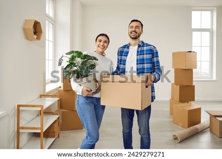 Happy young family couple moving into new apartment. Excited smiling husband and wife standing among cardboard boxes in new house. Real estate, residential mortgage concept Royalty-Free Stock Photo #2429279271
