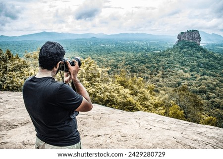 A photographer taking pictures of Sigiriya Rock Castle from the top of Pidurangala Rock in Sri Lanka.