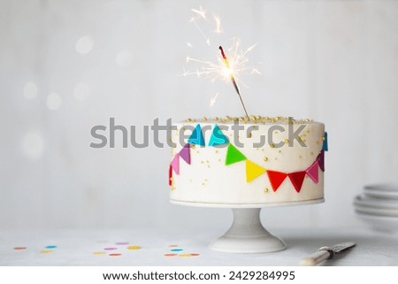 Celebration birthday cake with colorful rainbow bunting and a celebration sparkler Royalty-Free Stock Photo #2429284995