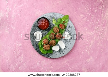 Traditional Asian street food meatballs served with krupuk prawn cracker and spicy chili sweet sour sauce on a Nordic design plate as top view with text space 