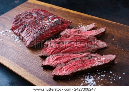 Traditional American barbecue bavette steak with salt and pepper served as close-up on a wooden design board  Royalty-Free Stock Photo #2429308247