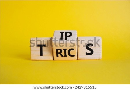 Tips and Tricks symbol. Wooden cubes with words Tricks and Tips. Beautiful yellow background. Business and Tips and Tricks concept. Copy space