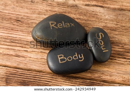 Photo of three lava stones for massage placed on old wooden board with very nice groovy texture.