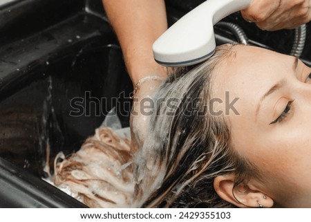 Stylist rinsing bleach to apply treatment to blonde hair. Woman in the beauty salon. Hairdresser and cosmetics. Royalty-Free Stock Photo #2429355103