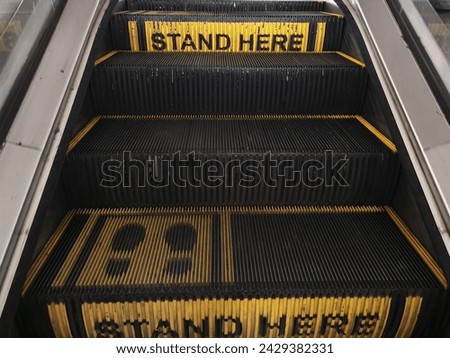 Elevator etiquette: A "Stand Here" sign guides passengers to the designated spot, ensuring proper spacing and safety within the confined space of the elevator.