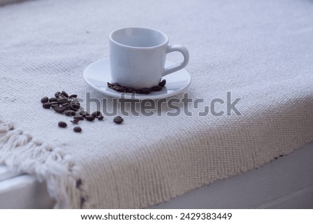 white coffee cup and beans on white tablecloth background close up photo with copy space