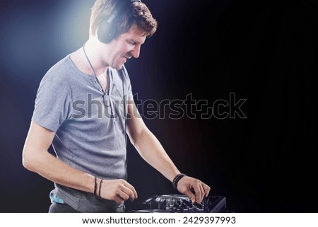 DJ deeply engrossed in his mix, with headphones on, focuses intently on the soundboard
