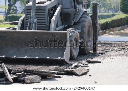 Excavator repairs broken roads, cracked asphalt roads.