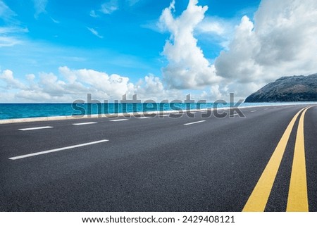 Asphalt highway road and blue lake with mountain nature landscape under blue sky