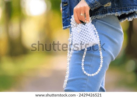 A stylish handbag in the hands of a young woman. Background with selective focus and copy space for text