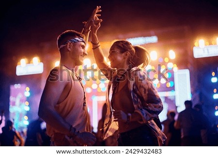 Carefree couple having fun while dancing on open air music concert at night.  Royalty-Free Stock Photo #2429432483