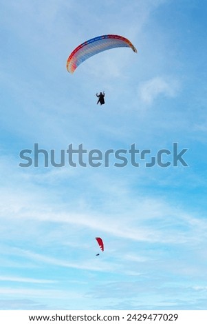 Two parachutes on cloudy sky background. Paragliding activity in Fethiye Oludeniz. Extreme sports idea concept. Vertical photo. Metaphorical meaning of freedom