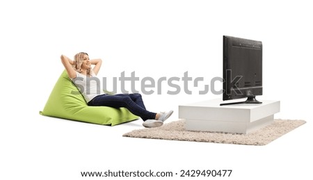 Relaxed woman sitting on a green beanbag chair and watching tv isolated on white background Royalty-Free Stock Photo #2429490477