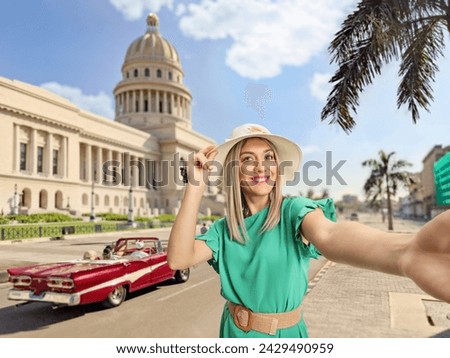 Happy young woman with a straw hat taking a selfie in front of El Capitolio building in Havana, Cuba