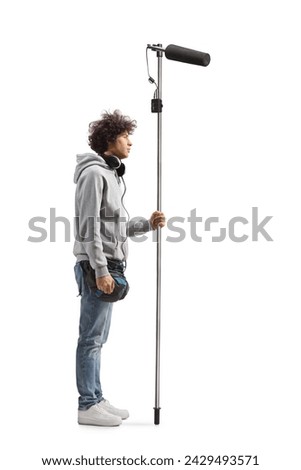 Full length profile shot of a boom operator holding a microphone isolated on white background