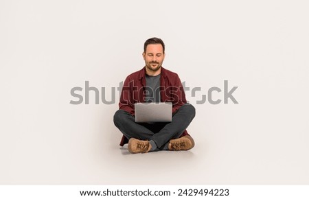 Full length of handsome entrepreneur checking e-mails over laptop while sitting on white background