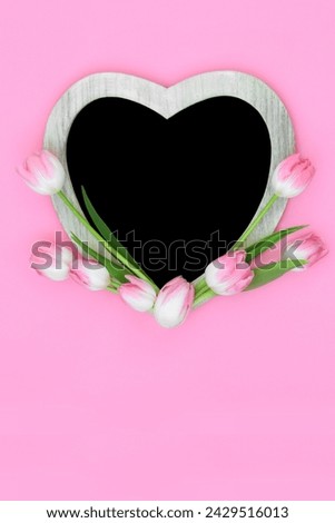 Heart shape pink tulip flower frame with chalkboard on pink background.. Minimal floral Spring, Mothers Day, Anniversary, birthday and Easter nature design.