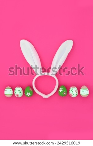Easter bunny ears fun headband with decorated eggs on vivid pink background. Abstract design for the holiday season.