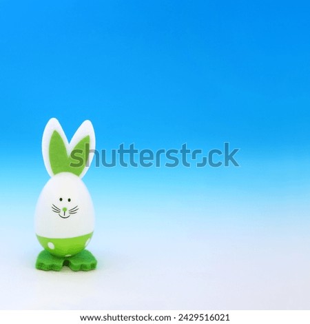 Easter bunny green egg on gradient blue white background. Minimal cute composition for the festive holiday season with go green environmentally friendly theme.
