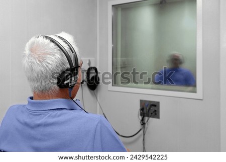 Audiologist woman doing the hearing exam to a mixed race man patient using an audiometer in a special audio room. Audiometric testing. Hearing loss treatment. Royalty-Free Stock Photo #2429542225