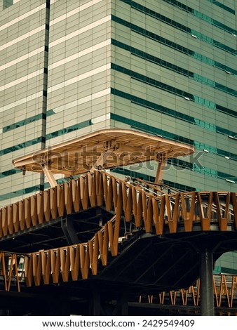 Modern pedestrian bridge with steel structure in orange and brown colors. This bridge connects two buildings in an urban area with different architectural designs.