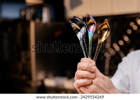 close-up of chrome professional spoons of tools in the hands of a chef in a professional kitchen