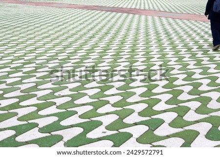 people walking on the road, path and pattern, man walking down a street next to a green and white pattern, A green and white patterned floor 