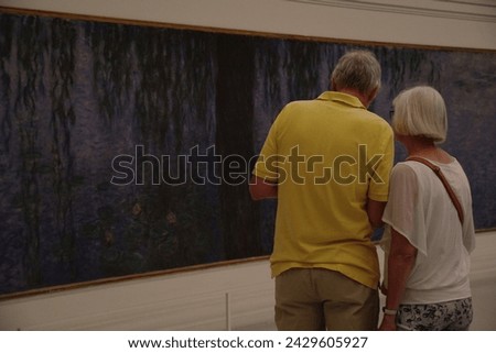 Paris, France-09032023:old couple looking at Monet's lilies painting in the Orangerie Museum Royalty-Free Stock Photo #2429605927
