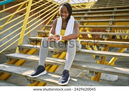 African american woman using stopwatch sitting on stairs at street