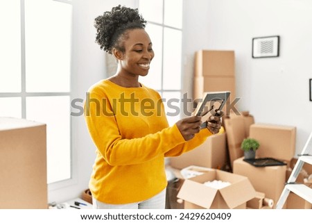 African american woman smiling confident looking photo at new home
