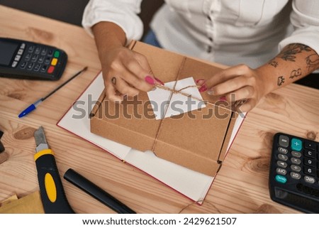 Young beautiful hispanic woman ecommerce business worker smiling confident preparing package at office