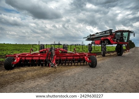 a new harrow cultivator, a self-propelled sprayer stands near a field of green beets Royalty-Free Stock Photo #2429630227