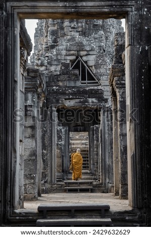 A monk coming to the ancient Hindu temple of Angkor Wat in Cambodia, Asia. Royalty-Free Stock Photo #2429632629