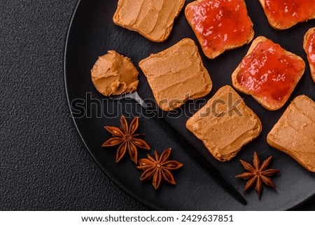Delicious nutritious sandwiches with peanut butter, strawberry jam on a dark concrete background