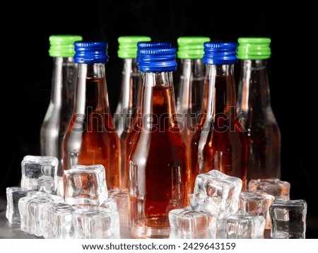 Small bottles of alcoholic drinks in ice cubes. Bottles with alcohol close-up.