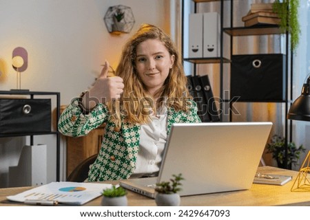 Like. Smiling Caucasian businesswoman looking approvingly at camera showing double thumbs up sign positive something good great news positive feedback. Happy girl using laptop at home office desk.