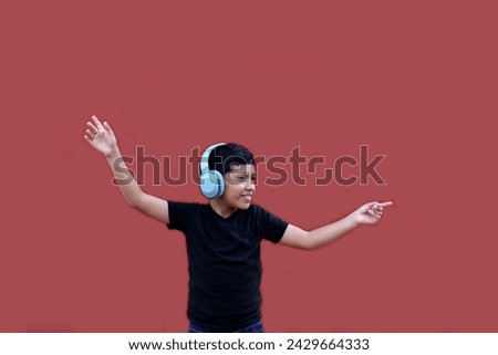9 year old Latino dark-skinned boy listens to music on his headphones and dances excitedly pointing out discounts and promotions